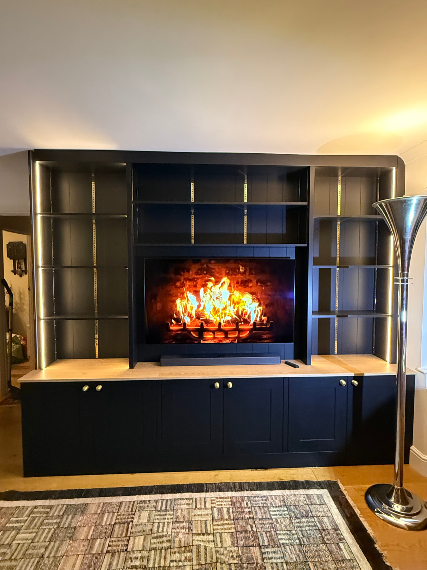 Bespoke media wall in navy painted joinery with inset screen and integrated fire